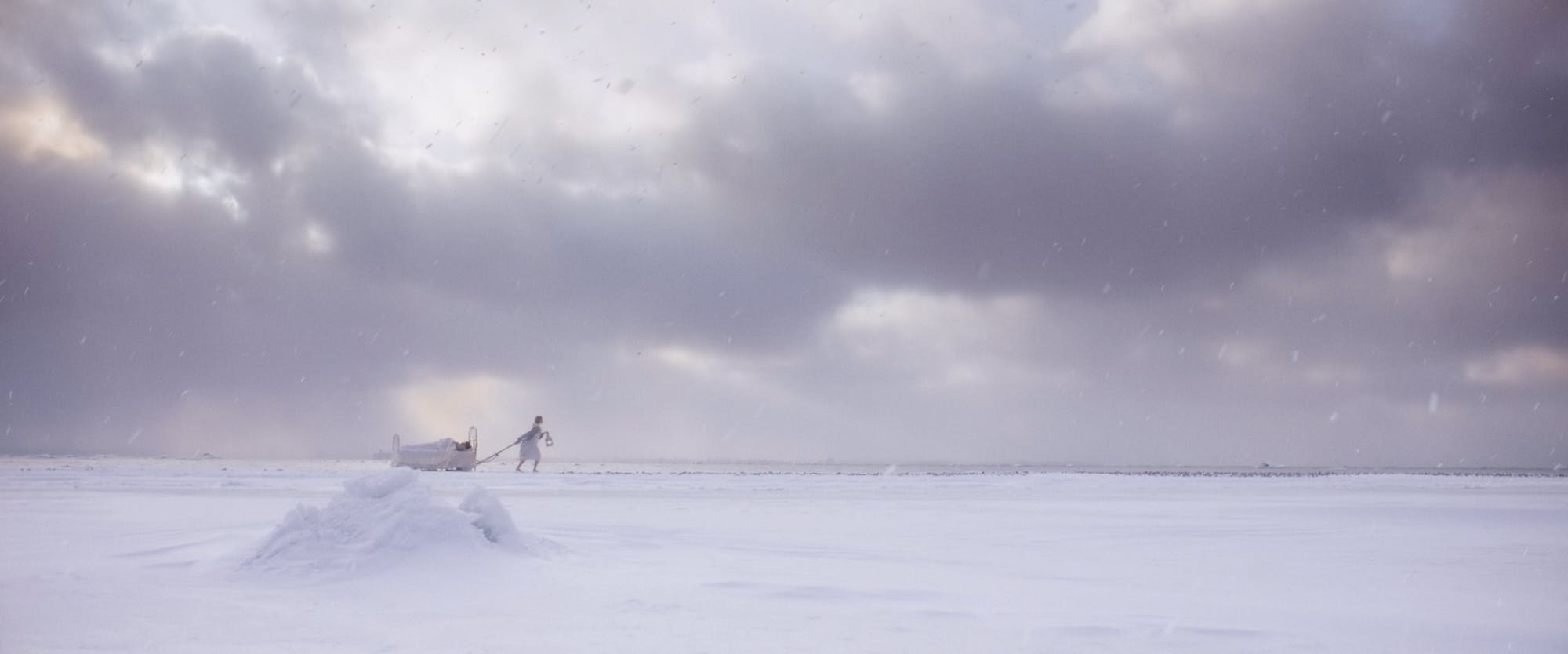 a girl dragging a bed in the ice field