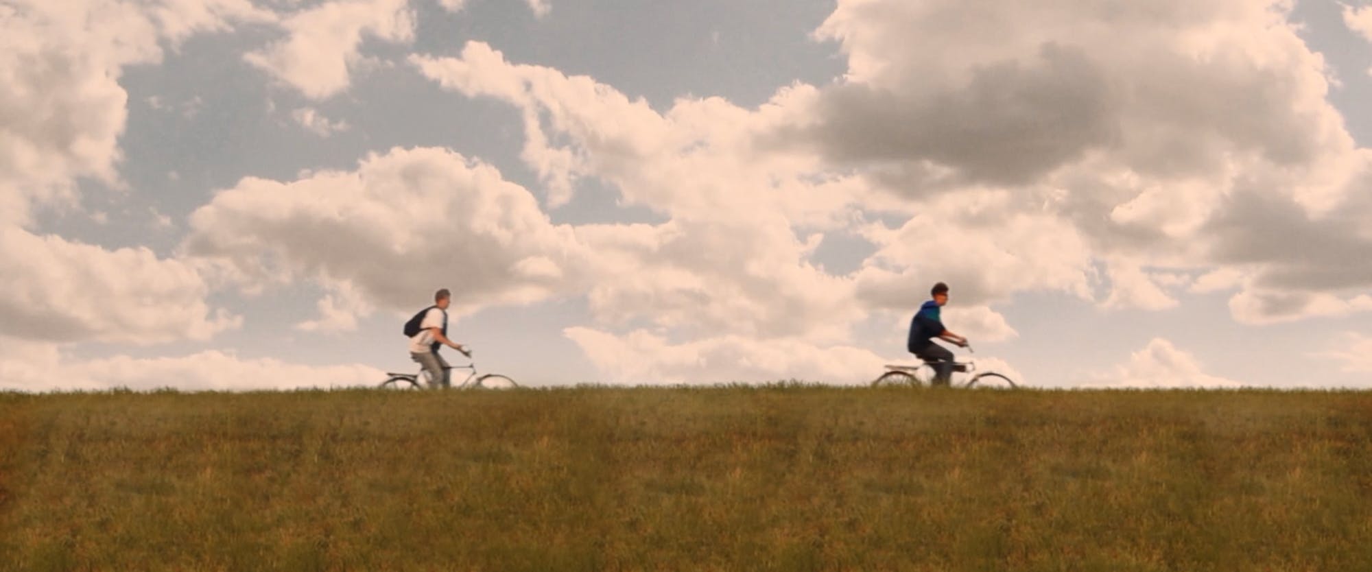 young guys driving bikes on top of a hill