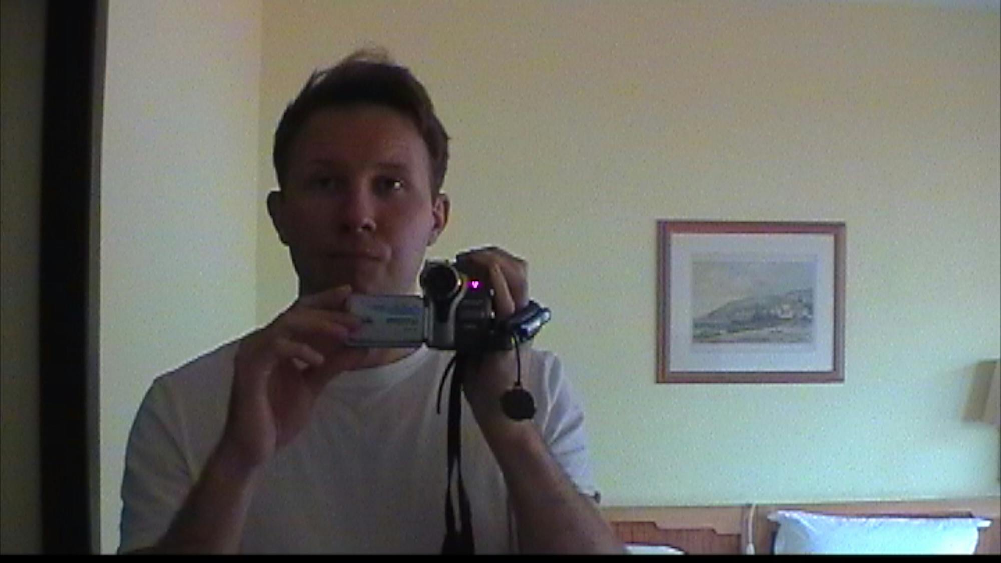 a man filming with an old miniDV camera himself in the mirror