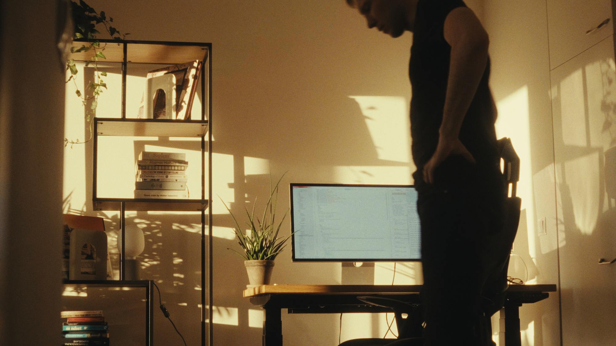 a sunny room with a computer and man walking